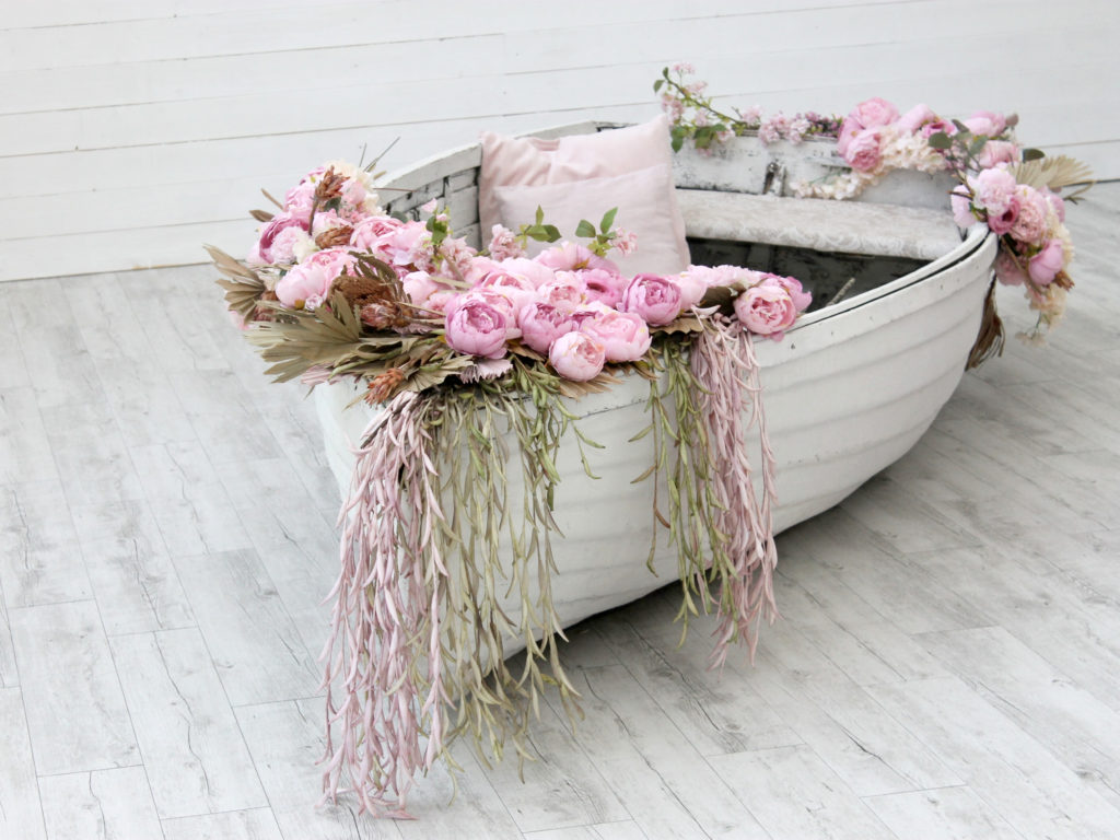 A white row boat with pink roses around it, roses are a contrubting factor to allergens in the air