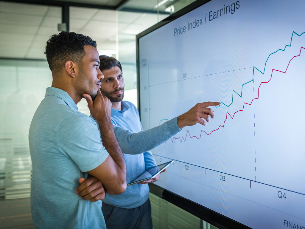 Two men are reviewing an earnings graph for their company, their company saw an increase during COVID-19.