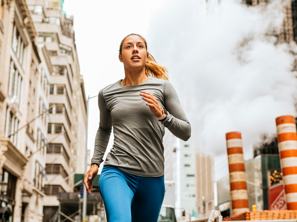 A woman running in the city, running improves cardiovascular health, however poor air quality indoors and outdoors has been linked to poor cardiovascular health.