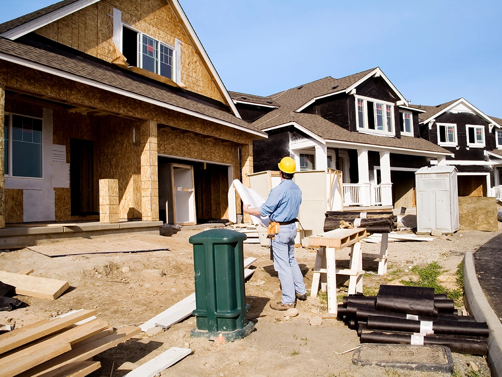 A contractor looking at blueprints in front of an unfinished new construction house, Homebuilder's are including solutions for IAQ in new houses and ActivePure is being considered by homebuilders across the nation.