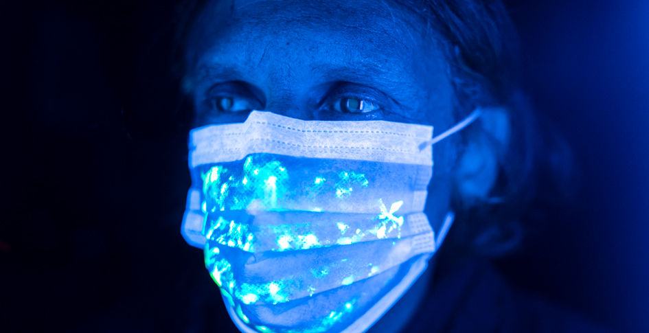 Man wearing a protective face mask under UV light.