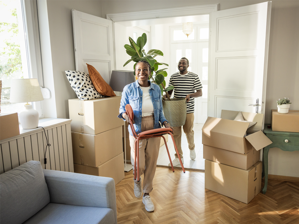 A man and a woman carrying furniture into a new house, formaldehyde is the result of off-gassing from construction materials such as foam insulation, wallpaper, and paints, used in construction of new homes.