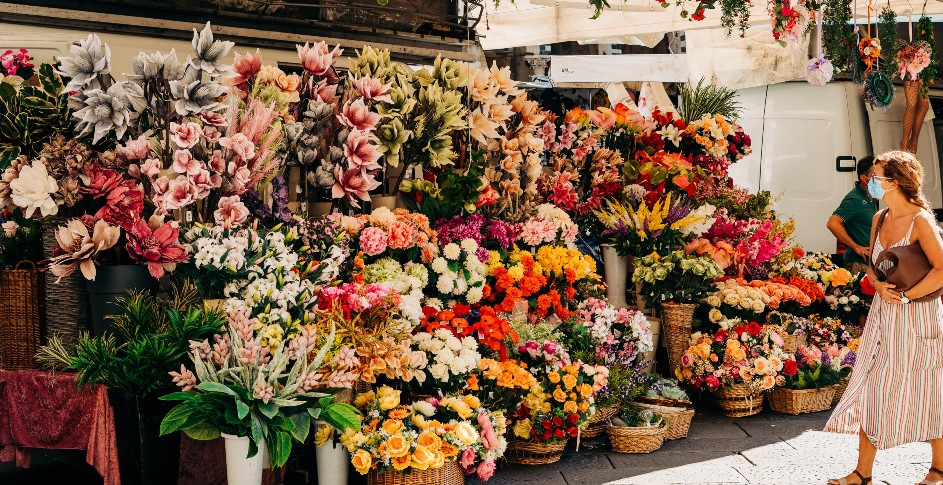 A flower stand with a woman glancing at selection, this spring an air purifier buying guide will help you decide if you need to filter from allergens like pollen.