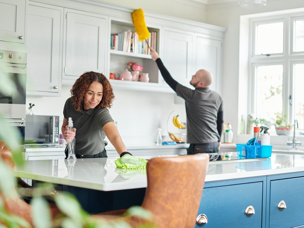 A couple cleaning their kitchen, cleaning frequency is crucial in controlling microbe populations in your kitchen.