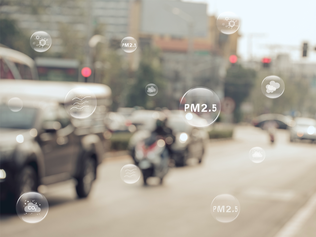 Blurry image of a street with cars and vehicles with bubbles representing components that affect air quality such as PM2.5 and CO2.