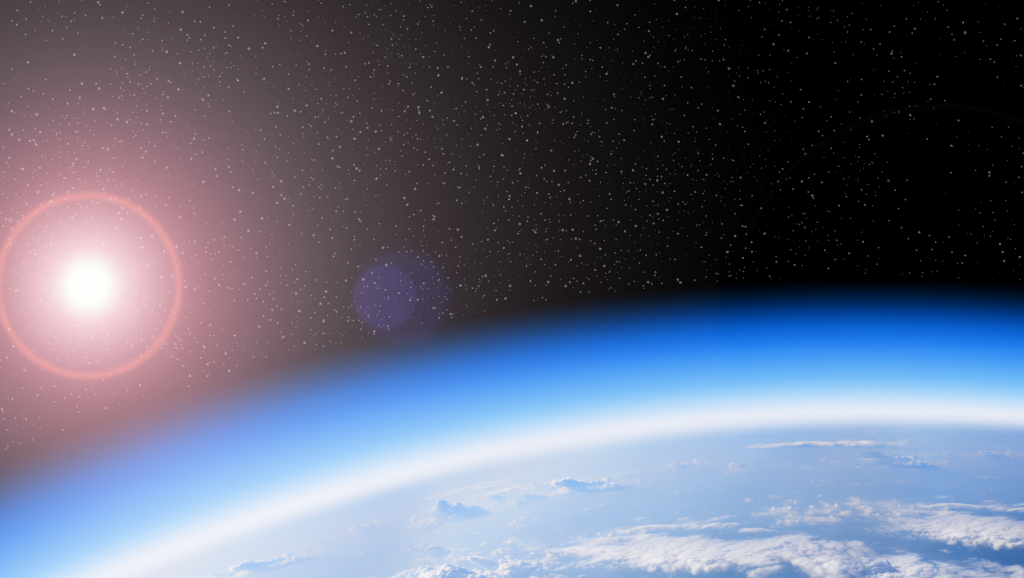 Earth from space, bright lue atmosphere with ozone and the sun ans stars shining in background