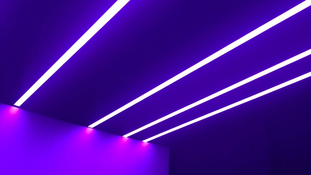 UV lights on ceiling in dark room, generating a purple hue in room.