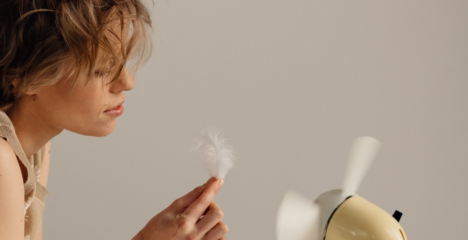 Woman holding feather in front of fan, indoor air quality is a significant concern in homes.