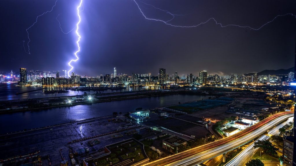 Very bright lightning bolt in a night sky of a city during a time lapse photo.